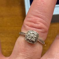 Ring worn on finger showing diamond cluster and band details