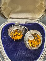 Front view of earrings showing amber rhinestones and silver-tone bezels