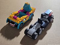 Two incomplete LEGO vehicles on cardboard surface