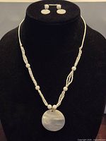 Full view of necklace and earrings on display bust