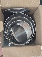 Open box showing nested stainless steel ring molds with press plate