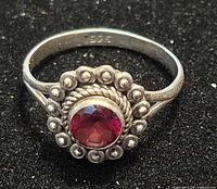 Front view of sterling silver garnet ring showing stone and halo design