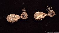 Full view of both drop earrings showing round and pear-shaped clear stones