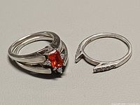 two sterling rings: red gemstone ring assembled with jacket, matching empty jacket beside