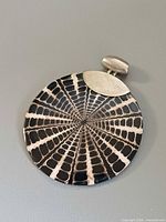 Front view of round spider shell pendant