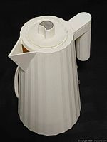 Front view of white pleated Alessi Plissé electric kettle with lid and cord