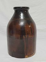 Front view of dark brown salt glazed stoneware jar showing rolled rim and drip glaze
