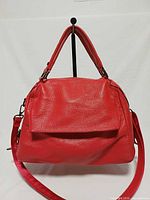 Front view of red pebbled leather satchel with dual handles and detachable strap