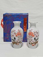 Front view of both vases showing painted bird and blossom design with presentation box.