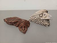 front view of both sculptures showing eagle head details and face on brown carving