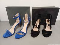 Both pairs of sandals in front of brand boxes