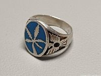 Oblique view showing bezel with turquoise inlay and cannabis leaf