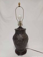 Full view of bronze metal Chinese style table lamp with bulb, harp, finial, base and cord