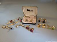 All items laid out showing variety of cufflinks, tie clips and tie tack