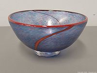 Oblique view showing bowl profile, red rim, mottled blue coloration and clear foot