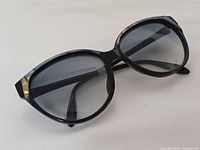 Front view of sunglasses showing black frame, multicolour brow accents, grey lenses