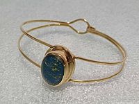 Cuff bracelet front view showing blue stone and gold-tone bands