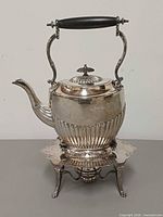 Front view of silver-plated spirit kettle on stand with burner showing overall form and condition