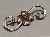 Front view of brooch showing sterling scrolls and copper dogwood flower