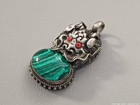Front view showing dragon motif, red eyes, malachite cabochon