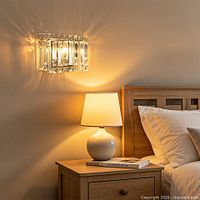 Sconce mounted above bedside table showing crystal prisms and chrome frame