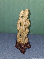 Front view of soapstone fisherman figurine on base