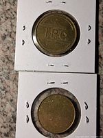 Close-up of both tokens in flips; I.P.C. marking visible, other side blank