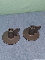 Two identical cast iron IKEA candle holders on blue surface