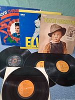 Three LP sleeves—Elvis’ Christmas Album, Elvis (blue cover), Elvis Country—four loose records below