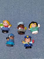 All five Fisher-Price Little People figures grouped on blue surface