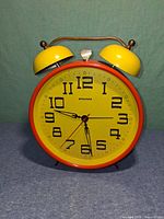 Front view showing clock face, bells and brass handle