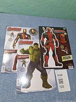Overall lot showing three sealed desktop standee sheets Deadpool, Hulk, Iron Man