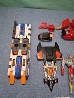 white/blue tracked vehicle, several connector parts, nose-cone section, action figure