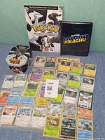 Group shot showing cards, Tepig tin, Black & White guide, Detective Pikachu binder