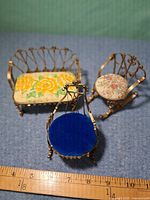 Front view of three miniature brass-tone furniture pieces