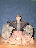 Front view of seated samurai doll with kimono layers visible