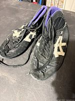 Top view of both shoes showing black fabric, off-white suede stripes, purple lining, frayed stitching