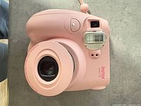 Front/top view of pink Fujifilm instax mini 7S with wrist strap attached