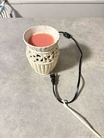 Full view of warmer with pink wax inside dish and attached cord visible