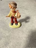 Front view of ceramic boy figurine holding sailboat