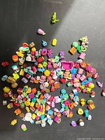 Wide view of dumped pile of assorted Shopkins figures on black surface