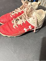 Side view of both cleats showing red/white color scheme and logos