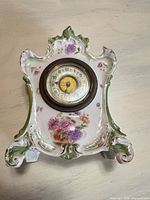 Front view showing complete porcelain clock case, dial and floral decoration