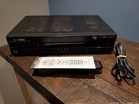 Front angled view of set-top box on table with remote, user guide and power cable