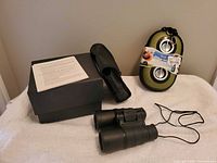 Speaker, binoculars, pouch, box, instruction sheet arranged on surface