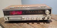 Front view showing LED clock display, AM/FM dial, 8-track slot, control knobs and headphone jack