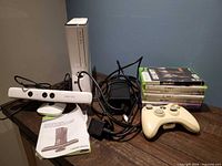Console, Kinect sensor, controller, power brick, manual, game stack on table