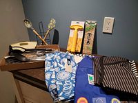 Full lot showing aprons, towels, placemats, utensils box, pineapple corer, sushi mat