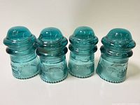Front view of four aqua Hemingray No. 9 insulators