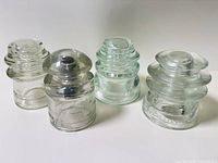 Front view of four Hemingray glass insulators showing colors and shapes